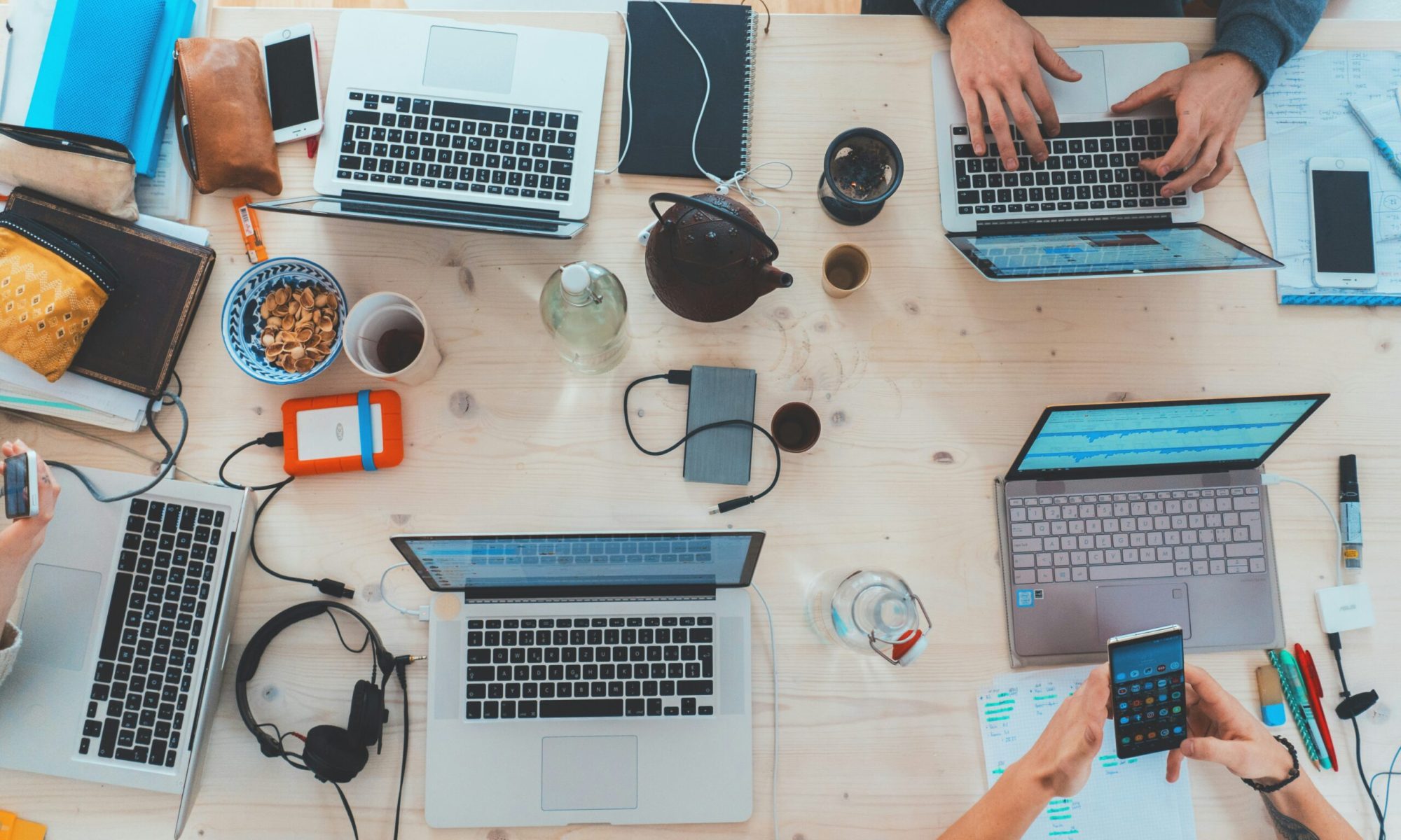 people sitting down near table with assorted laptop computers